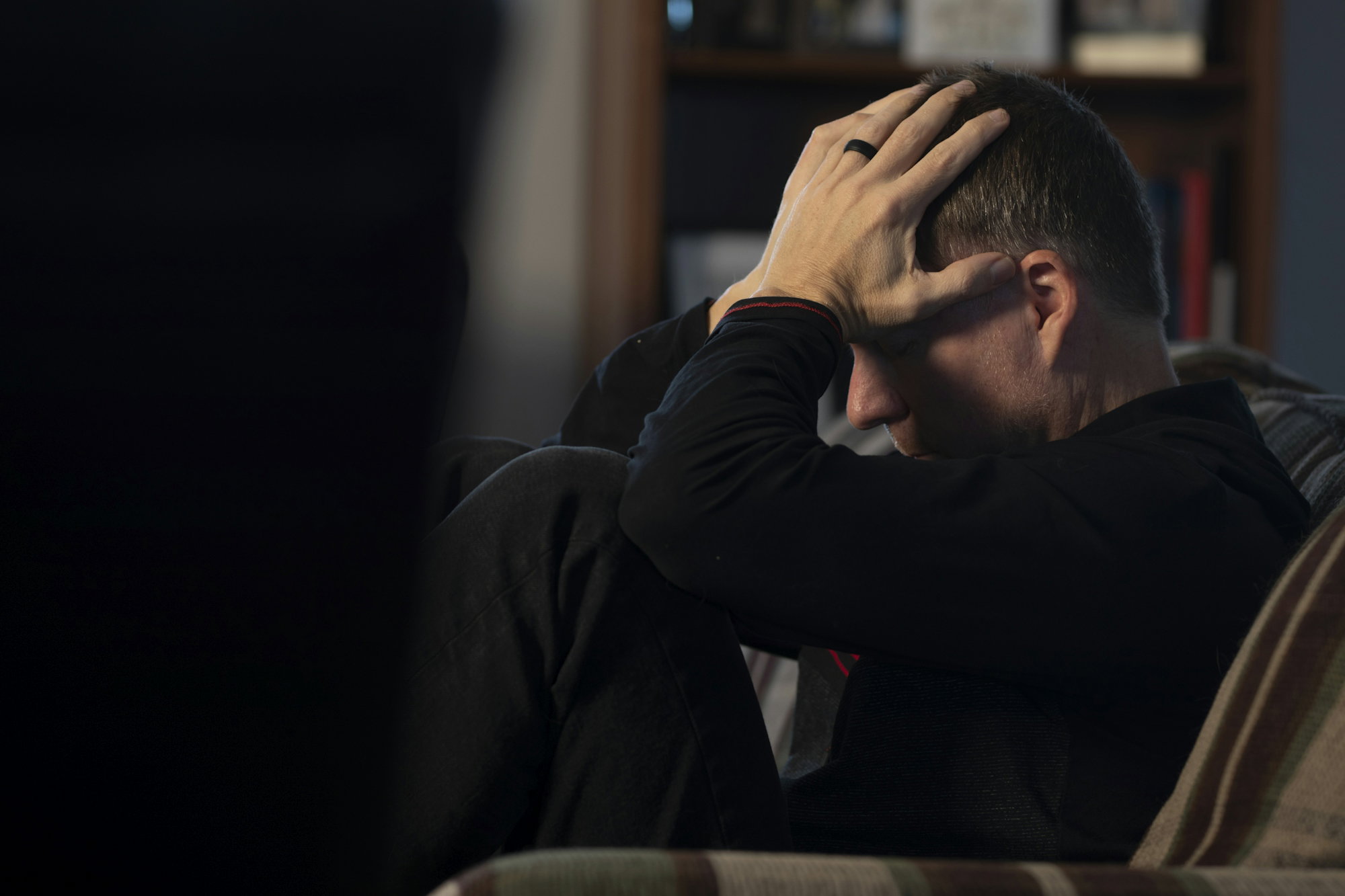 a-man-sitting-on-a-couch-holding-his-head-in-his-hands.jpg a man sitting on a couch holding his head in his hands